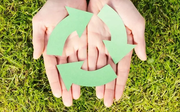 deux mains sur une feuille désignant le logo du seconde main, eco responsable